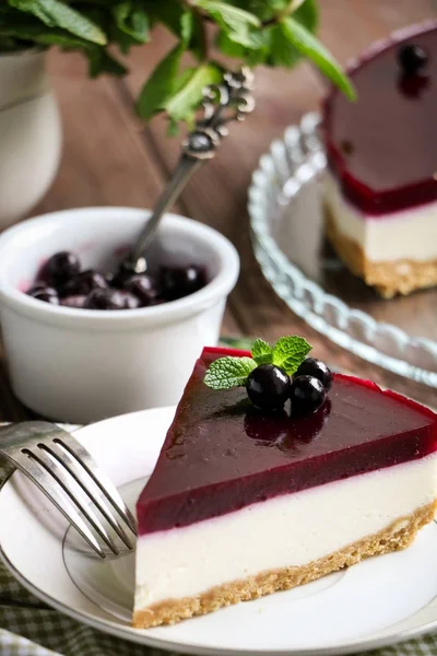 leziz cheesecake bir cam tabak, nane yaprakları ve Frenk üzümü berries.a kase çilek ve vintage bir kaşık ile Siyah frenk üzümü tabakası ile kahverengi ahşap masanın üzerine nane ile küçük bir beyaz sürahi şubeleri
