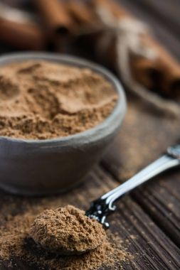 ahşap arka plan üzerinde iple bağlı tarçın tarçın, tarçın, bir el yapımı kil kase bir vintage kaşıkla yakın çekim.