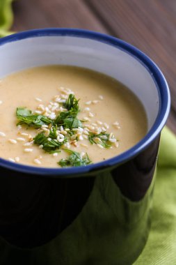 Kabak Krem çorbası susam ve maydanoz ile bir fincan bir kahverengi ahşap arka plan üzerinde yakın bırakır