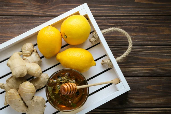 Üç limon, tatlı bal kase ve baharatlı ginger, kahverengi ahşap masada iki kökleri ile beyaz ahşap tepsi