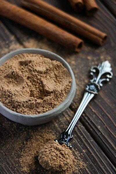 el yapımı kil kase, vintage kaşık, aromatik tarçın tarçın arka yüzü, kahverengi ahşap masada yapışıyor.