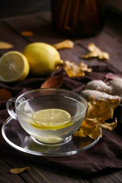 bir cam fincan limon ve grip ve soğuk karşı korur, baharatlı ginger ile yararlı çay Makinası Tekstil kahverengi peçete, sonbahar yaprakları koyu kahverengi ahşap tablo