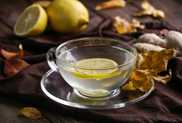 bir cam fincan limon ve grip ve soğuk karşı korur, baharatlı ginger ile yararlı çay Makinası Tekstil kahverengi peçete, sonbahar yaprakları kahverengi ahşap tablo