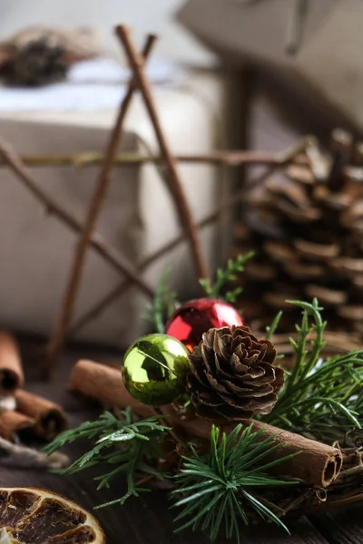 New year decoration elements and gifts in craft wrapping paper, wooden star of tree branches, sticks of cinnamon and christmas toys, fir cones — Stock Photo, Image