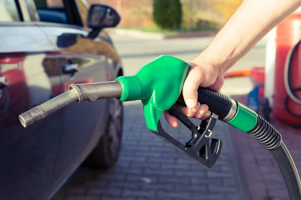 Man handen håller bensin pumpen i en bensinstation — Stockfoto