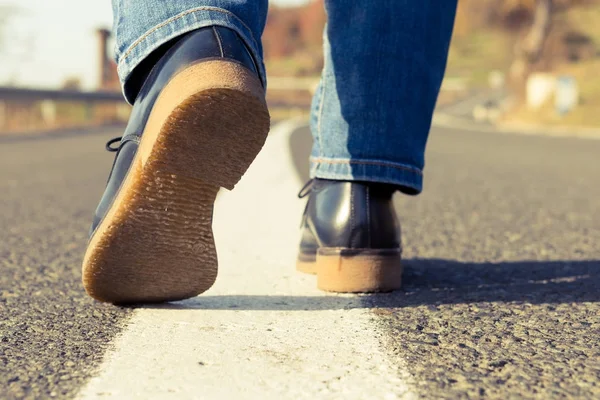 Woman feet walking on the middle of a country side road — Stock Photo, Image