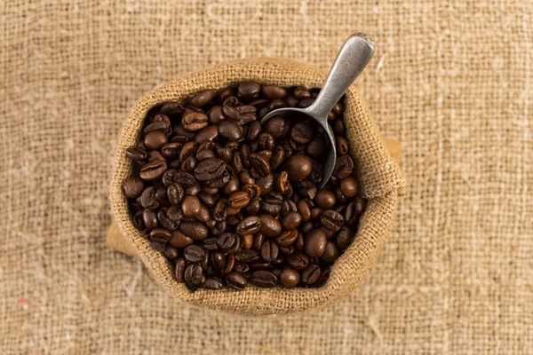 Vista superior do saco de café no fundo de juta marrom — Fotografia de Stock