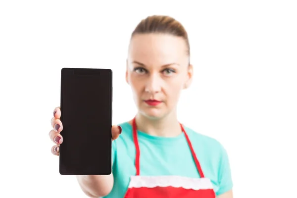 Donna con grembiule rosso che mostra smartphone o cellulare vuoto s — Foto Stock