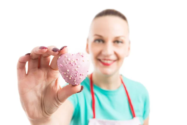 Red apron woman showing hearth shape gingerbread — Stock Photo, Image
