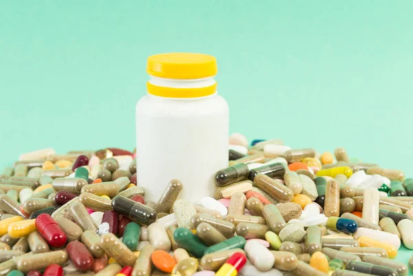 Muchas píldoras al azar con recipiente de plástico — Foto de Stock