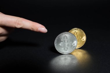 Bitcoins koyu arka plan üzerinde işaret parmak