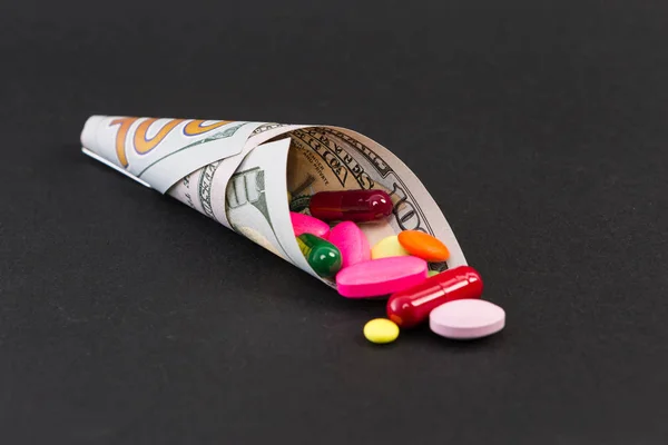 Comprimidos e cápsulas envolto em uma nota de cem dólares — Fotografia de Stock