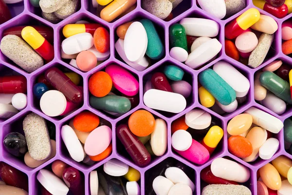 Varias píldoras y cápsulas en el peine celular organizar — Foto de Stock