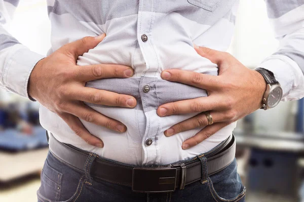 Man trycka uppsvälld buken eller mage som kramp flatulens problem — Stockfoto