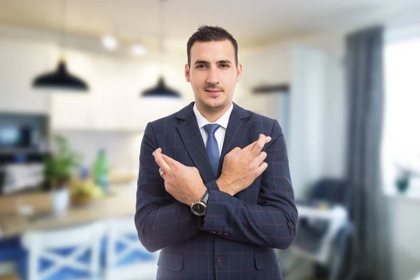 Agente immobiliare con le dita incrociate su backgroun interni — Foto Stock