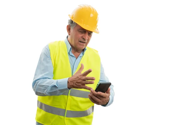 Construtor olhando para o telefone com expressão irritada — Fotografia de Stock