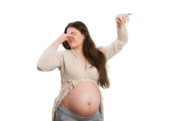 Pregnant woman grabbing broken cigarette while holding nose as unhealthy habit concept isolated on white background