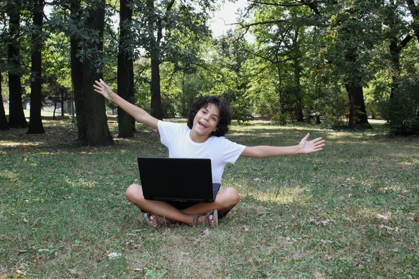 Un garçon bouclé avec un ordinateur portable — Photo