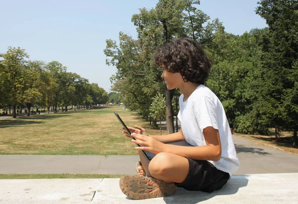 Um menino encaracolado com um laptop — Fotografia de Stock