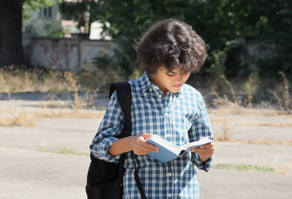 Ein lockiger Schuljunge mit einem Buch — Stockfoto