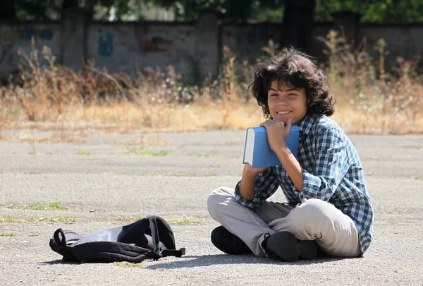 Un écolier bouclé avec un livre — Photo
