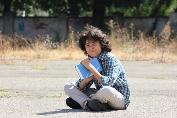 Un écolier bouclé avec un livre — Photo