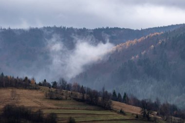 Yüksek dağların tepeleri bulutlarla gizlidir. Sis. Sonbahar manzarası. Panoramik görünüm.