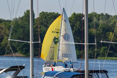 Kyiv Ukrayna, Dinyeper Nehri 25 Temmuz 2019. İnsanlar Yat Kulübü 'nde kiralanan yatlarda yelken açarlar. Orada insanlar yat kiralayabilir ve sürüş dersleri alabilirler. Sarı ve beyaz yelkenli beyaz bir yat.