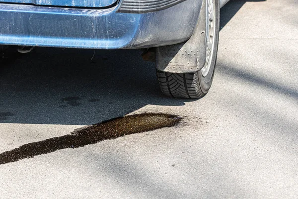Park halindeki bir arabadan asfalta benzin damlaları akıyor. Yanıcı motor yakıtı ile çevre kirliliği. Ateş riski var. Eski hatalı yolcu vagonu.