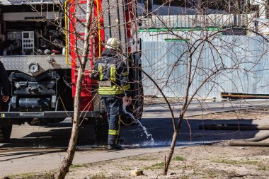 Yangından çıktıktan sonra, bir itfaiyeci özel bir arabanın itfaiyecisinin yanında ayakkabılarını soğuk suyla ıslatır. Yangın koruma giysisi giymiş bir itfaiyeci. Gerçek bir yangının söndürülmesi..
