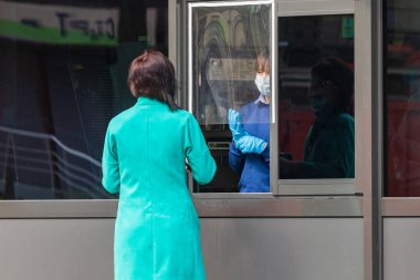 Kyiv Ukrayna - Nisan 01 2020: Koruyucu maske ve koruyucu eldivenli bir çalışan, fast food restoranlarında yiyecek dağıtmak için korunan bir pencerenin yanında duruyor. Büyük şehirlerde karantina