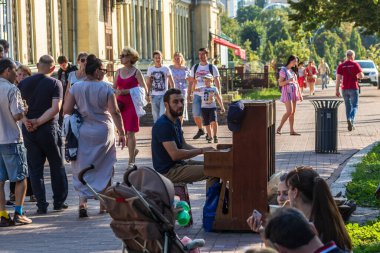 Kyiv Ukrayna - 27 Temmuz 2019: Kimliği belirsiz müzisyen Kyiv 'in merkezindeki Mikhailovskaya Meydanı' nda bir piyanoda çalıyor. Sokak kültürü. Açık havada. Yakın plan..