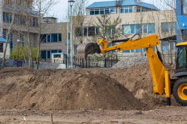 İnşaat alanındaki toprak işlerinde kazıcı yükleyici. Kazı makinesi yeni bir park alanı inşa ediyor..