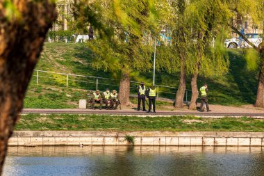Kyiv Ukrayna - 17 Nisan 2020: Dünya koronavirüsü salgını. Koronavirüs nedeniyle karantina sırasında, polis memurları ve sağlık maskeli ulusal muhafız şehir parkında devriye geziyor..