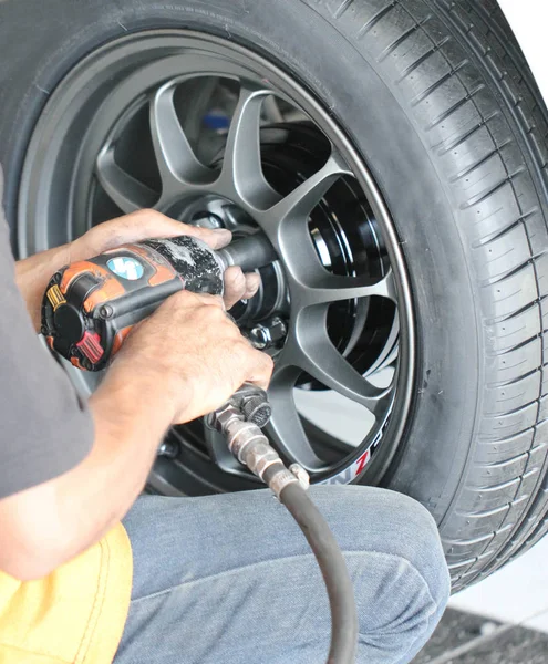 Parafuso mecânico do carro ou desparafusar a roda do automóvel levantado pela chave pneumática na estação de serviço de reparação — Fotografia de Stock