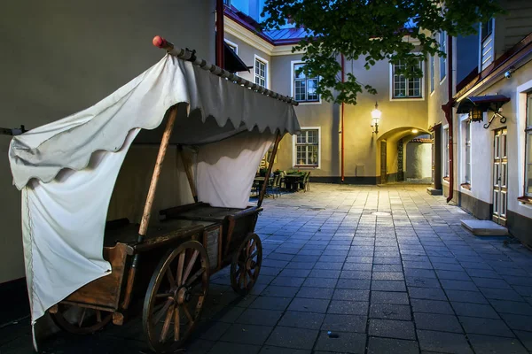 Histórico negociando o carro em uma rua estreita da cidade velha. Pequeno pátio colorido e medieval em Tallinn. Atracção na Estónia. Noites brancas na temporada de verão . Fotos De Bancos De Imagens