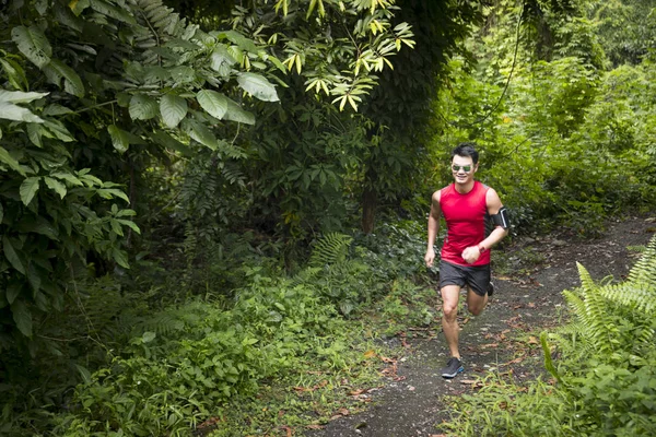 Asian man running on forest trail