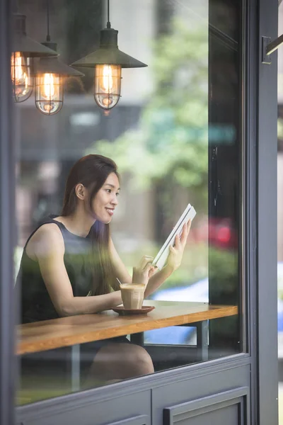 Asian Businesswoman with coffee reading tablet
