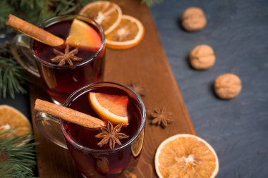 Noel şarabı portakal dilimli iki kadehte baharatlı tarçınlı kırmızı şarap ve siyah arka planda yıldız anasonlu. En üstteki manzara..
