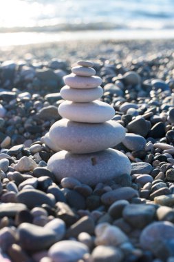 pyramid of pebbles on the beach sea. illuminated by the sun.