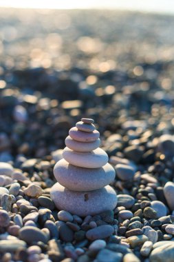 pyramid of pebbles on the beach sea. illuminated by the sun.