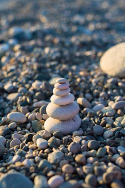 pyramid of pebbles on the beach sea. illuminated by the sun.