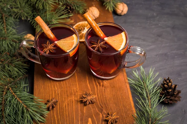 Vino brulé caldo natalizio con cardamomo, cannella e anice su fondo ligneo. sullo sfondo di rami di abete, noci e arance . — Foto Stock