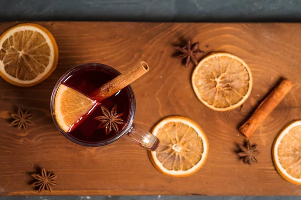 winter spicy drink mulled wine based on red wine, spices and orange. on a dark wooden background. close-up, space for text . the view from the top