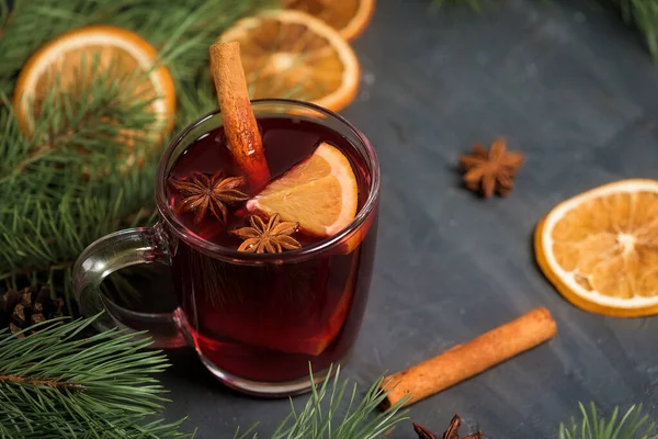winter spicy drink mulled wine based on red wine, spices and orange. on a dark background with fir branches, orange slices . close-up, space for text . the view from the top