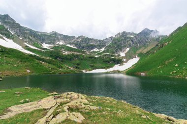 Dağlarda göl, mavi su. Etrafta karlı dağlar var. Dağlık arazinin manzarası