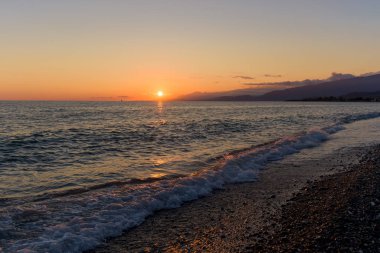 Denizde gün batımı. Turuncu gökyüzü, denizin dalgaları