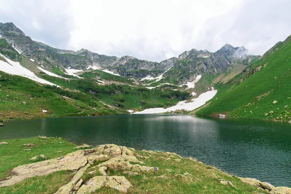 Tó a hegyekben, kék víz. havas hegyek körül. panoráma hegyvidéki terepre — Stock Fotó