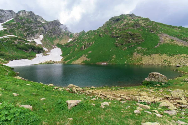 Lac dans les montagnes, eau bleue. montagnes enneigées autour. panorama du terrain montagneux — Photo