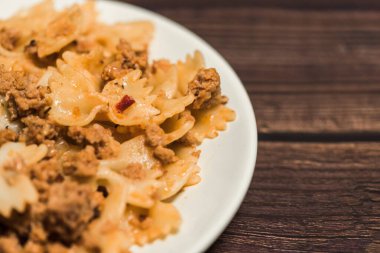 Elinde çatalla ahşap bir arka planda etli makarna. afiş için fotoğraf, metin için yer